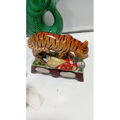 10 - A group of glazed ceramic animal figures and novelty wares, including a model cow, perched parrot, t... 