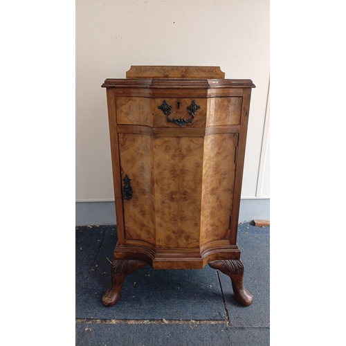 Late Victorian burr-walnut veneered  bedside cabinet, the breakfront top with low three-quarter gallery above a single drawer and cupboard door, fitted with cast metal swan-neck handle and escutcheon, raised on carved cabriole supports. Height  30 inches x width 16 inches x depth 16.5 inches.
