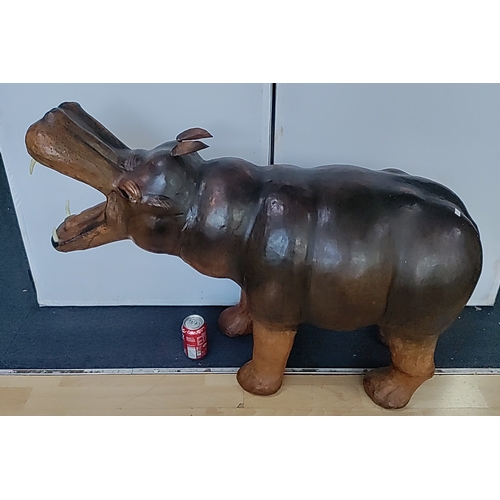 Leather Liberty style hippopotamus sculpture, modelled standing with open jaws, inset tusks and pricked ears; the body rendered with simplified musculature and striated back, finished in polychrome in shades of brown and black - L95cm x W35cm x H70cm
