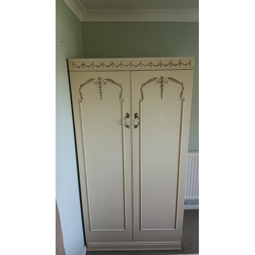 A Louis Xiv style wardrobe, the cornice applied with gilt floral swags; the doors with rocaille mouldings and gilt-metal handles, opening to a fitted interior. Height 69.5 inches x width 36 inches x depth 21 inches.