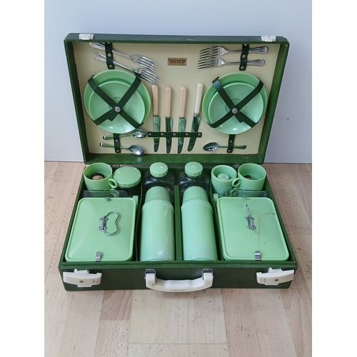 Brexton picnic hamper, made in England, fitted with green plastic tableware including plates, cups, canisters, covered tins, thermos flasks, and chrome cutlery with ivorine-style handles, in a green case with strap fittings. Height 5 and a half inches x Width 24 and a half inches x Depth 12 and a half inches.
