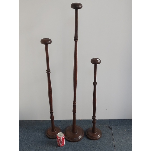A set of three turned hardwood hat stands, each with domed circular top and ring-turned baluster shaft, raised on stepped circular bases - Tallest 118cm