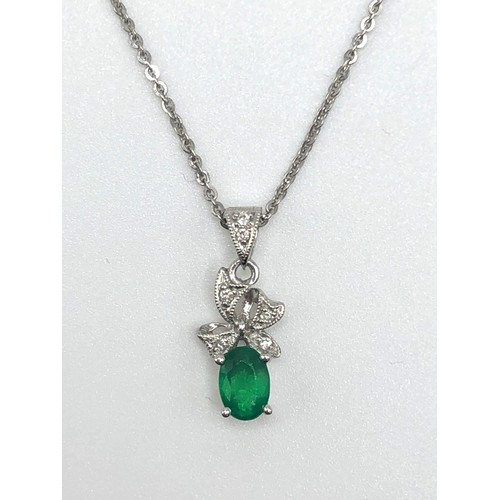 180 - A 0.4ct emerald set in a diamond and 18ct white gold pendant with an 18ct white gold chain. 2.7g