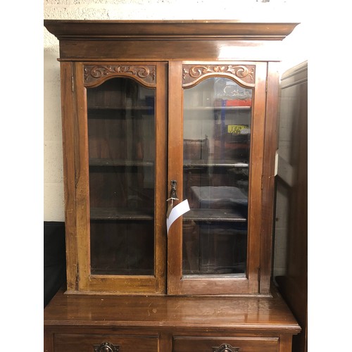 350 - A two-door wooden book/display case with glass panels, decorative floral craving to top of the panel... 