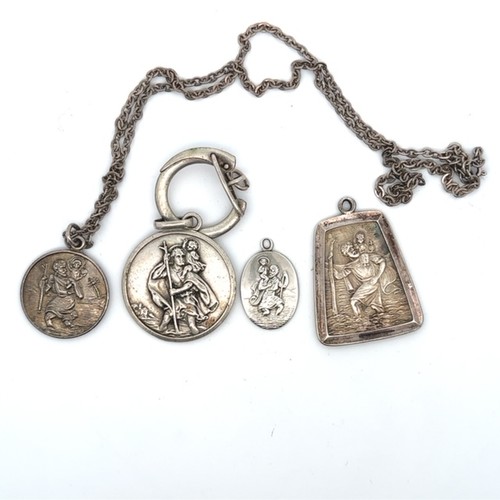 305 - Four silver St Christopher pendants, one with chain. Two are stamped 'silver', the smaller oval pend... 