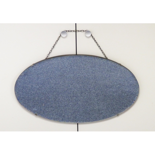 312 - A frameless oval shaped wall mirror, wooden backed with the glass held via four clasps. Chain hangin... 