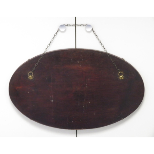 312 - A frameless oval shaped wall mirror, wooden backed with the glass held via four clasps. Chain hangin... 