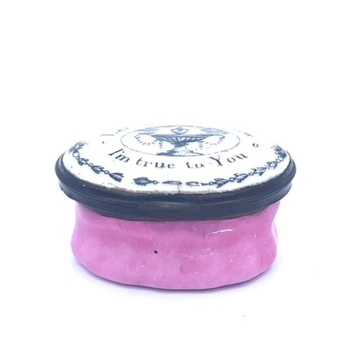 57 - A Bilston oval enamel patch box with a pink fluted base and a hinged monochrome lid with the motto '... 