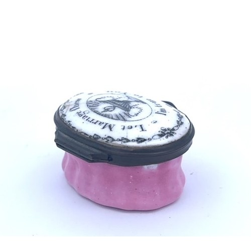 57 - A Bilston oval enamel patch box with a pink fluted base and a hinged monochrome lid with the motto '... 