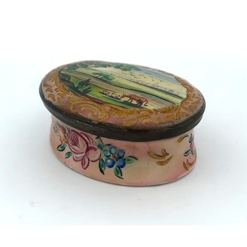 62 - A Battersea/ Bilston hand painted enamel patch box with hinged lid depicting a rural scene and a flo... 