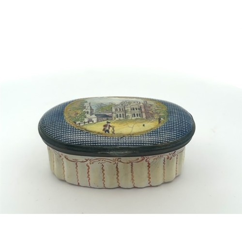 63 - An oval enamel pill/ patch box, probably Bilston with fluted body and painted lid depicting a church... 