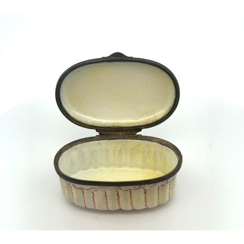 63 - An oval enamel pill/ patch box, probably Bilston with fluted body and painted lid depicting a church... 