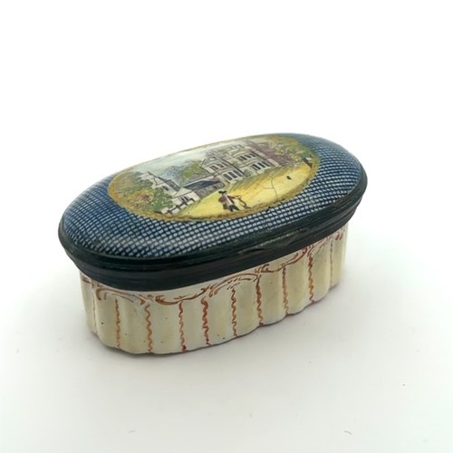 63 - An oval enamel pill/ patch box, probably Bilston with fluted body and painted lid depicting a church... 