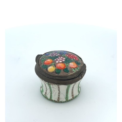 64 - Round enamel box with floral picture on hinged lid and green and gold design on body. Approx 33mm di... 