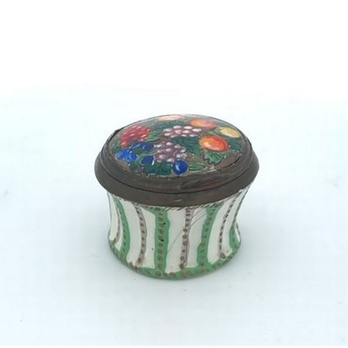 64 - Round enamel box with floral picture on hinged lid and green and gold design on body. Approx 33mm di... 