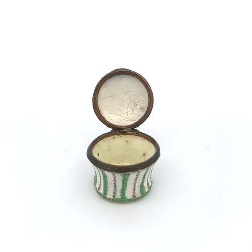 64 - Round enamel box with floral picture on hinged lid and green and gold design on body. Approx 33mm di... 