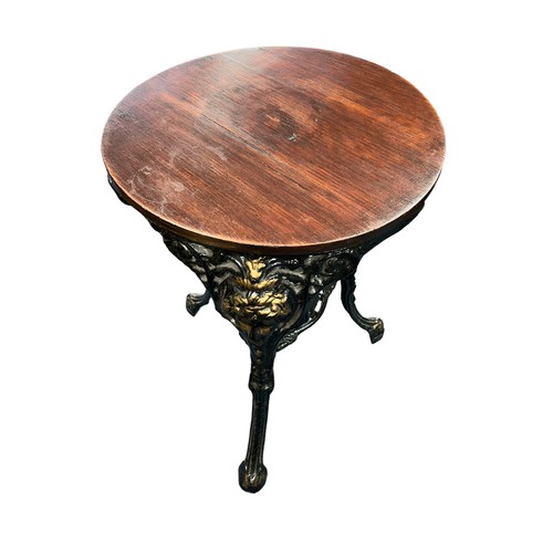 275 - A three legged pub table with cast iron painted legs, each leg with a face design at the top. Wooden... 