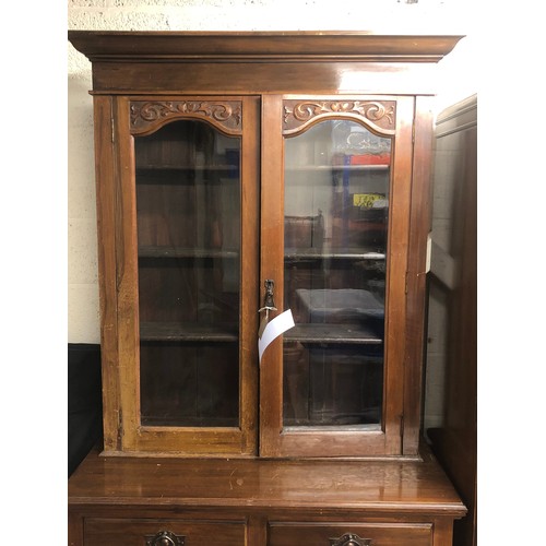 303 - A two-door wooden book/display case with glass panels, decorative floral craving to top of the panel... 