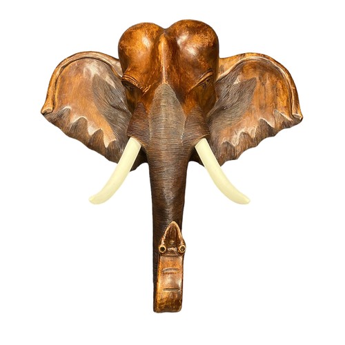 281 - A large wooden wall mounted wooden Elephant head with white painted tusks. Height 100cm, Width 100cm... 