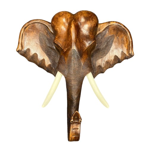 281 - A large wooden wall mounted wooden Elephant head with white painted tusks. Height 100cm, Width 100cm... 