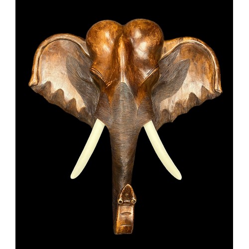 281 - A large wooden wall mounted wooden Elephant head with white painted tusks. Height 100cm, Width 100cm... 