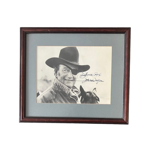 544 - John Wayne (1907-1979) – A framed black and white photograph signed by John Wayne in black ink “Good... 