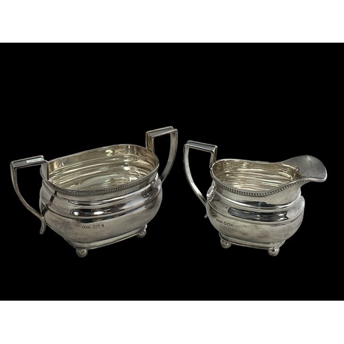 204 - A silver milk / cream jug and sugar bowl with ball feet, gadroon rim and plain handles with raised e... 