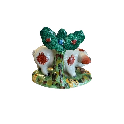 418 - Staffordshire, a Staffordshire hand painted Pig figurine stood before a tree. Height 12cm.