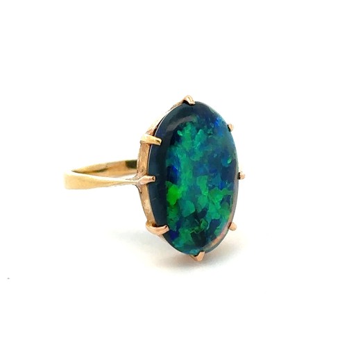 15 - A solid black opal ring set in 18ct yellow gold, showing good blue and green play of colour. Opal ap... 