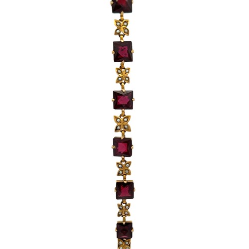 37 - A yellow metal bracelet set with 10 square cut garnets interspersed with flower shaped links each se... 