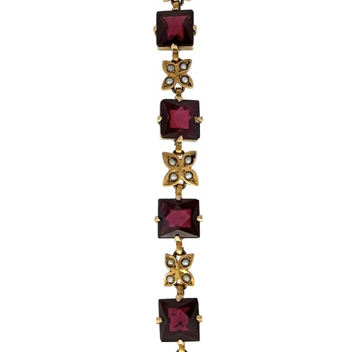 37 - A yellow metal bracelet set with 10 square cut garnets interspersed with flower shaped links each se... 