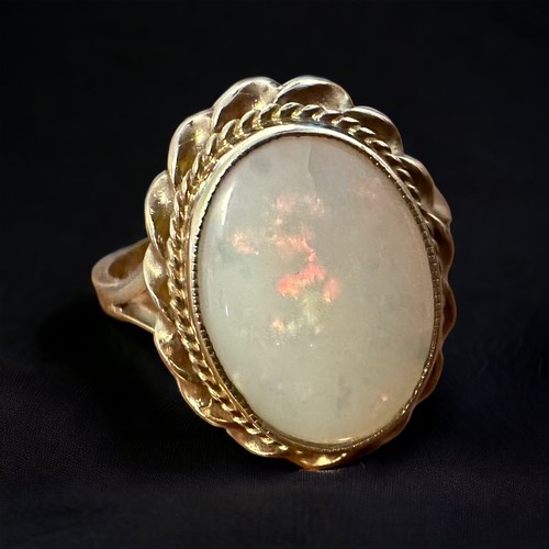 39 - A 9ct opal ring -  oval opal cabochon with gold rope twist surround, size Q. Small crack in the bott... 