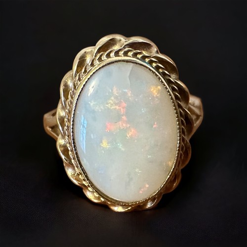 39 - A 9ct opal ring -  oval opal cabochon with gold rope twist surround, size Q. Small crack in the bott... 