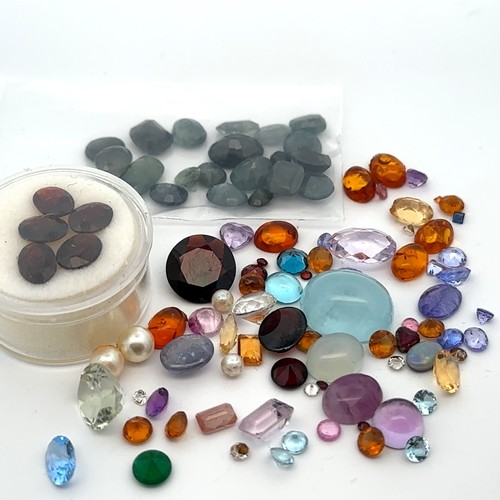 114 - An assortment of loose unmounted gemstones including aquamarine, topaz, tourmaline, garnet, tanzanit... 