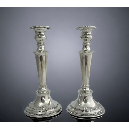 199 - A pair of silver candlesticks with beaded edges, supported on stepped circular bases and with origin... 