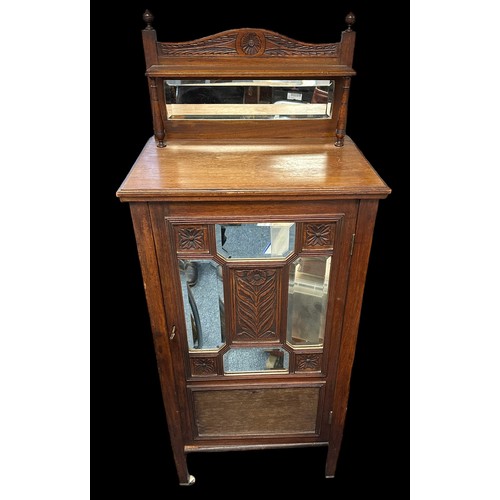 410 - Edwardian walnut music cabinet with mirror inset upstand, the partly glazed panelled door also with ... 