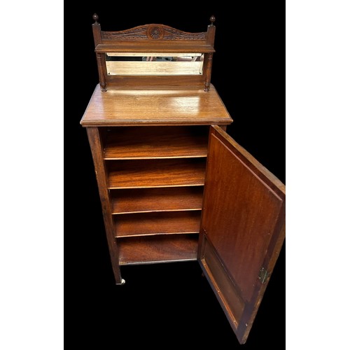 410 - Edwardian walnut music cabinet with mirror inset upstand, the partly glazed panelled door also with ... 