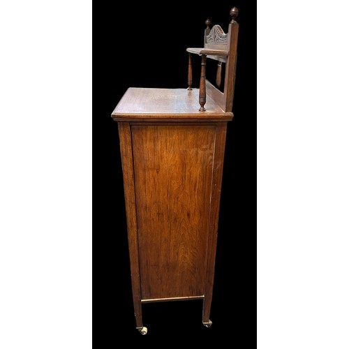 410 - Edwardian walnut music cabinet with mirror inset upstand, the partly glazed panelled door also with ... 