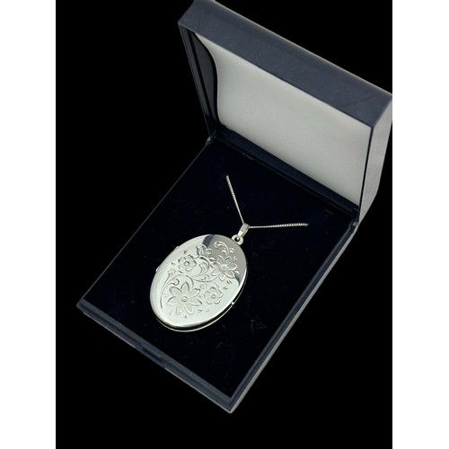 52 - A silver locket with foliate design stamped 'Germany MM 925'  on a white metal chain. Locket 4cm in ... 