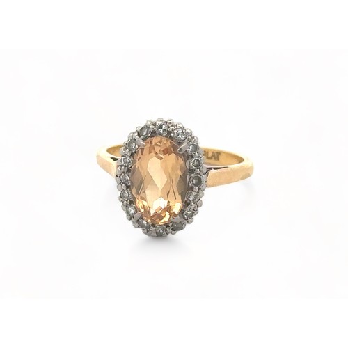 27 - An oval imperial topaz and diamond cluster ring, stamped 18ct and PLAT, by maker W.E.G. Topaz approx... 