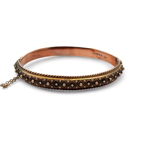 9 - An Edwardian bangle with fancy metal work and rope twist edging. 9ct rose gold with hallmarks for Ch... 