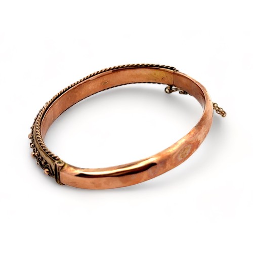 9 - An Edwardian bangle with fancy metal work and rope twist edging. 9ct rose gold with hallmarks for Ch... 