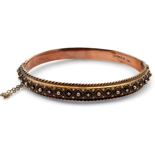 9 - An Edwardian bangle with fancy metal work and rope twist edging. 9ct rose gold with hallmarks for Ch... 