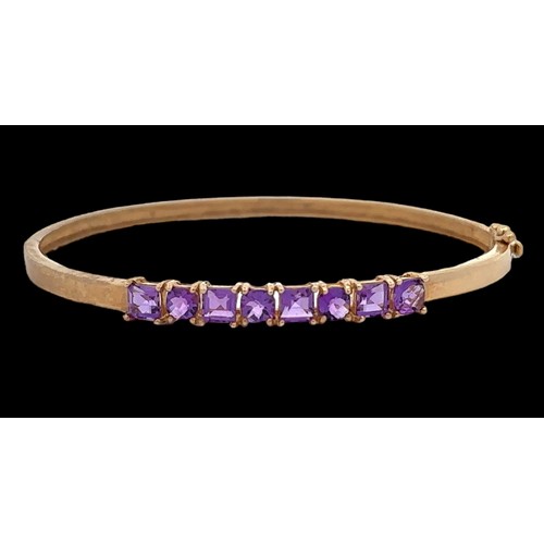 8 - A small 9ct gold hinged bangle set with eight purple gemstones, likely CZs,  alternating square cut ... 