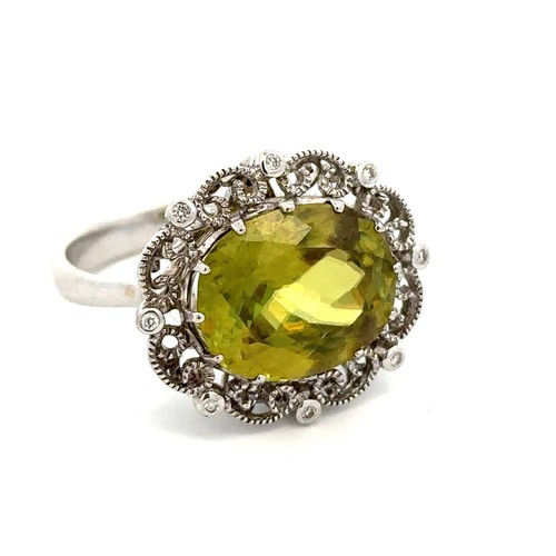 29 - A sphene and diamond ring, size P/Q. The oval cut sphene of approx 14mm x 11mm is set in an umarked ... 