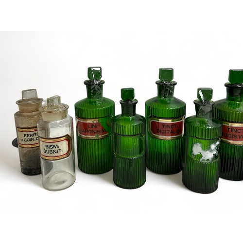 290 - 13 Apothecary Jars: Seven green jars with fluted sides and chisel stoppers, 3 are 21cm x 8cm, one is... 