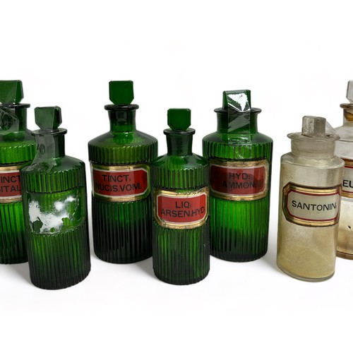 290 - 13 Apothecary Jars: Seven green jars with fluted sides and chisel stoppers, 3 are 21cm x 8cm, one is... 