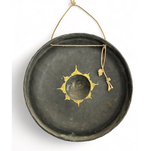 336 - Burmese black lacquered metal nipple gong decorated with four gilt figures, diameter 25cm. With wood... 