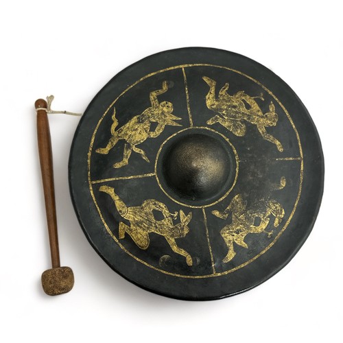 336 - Burmese black lacquered metal nipple gong decorated with four gilt figures, diameter 25cm. With wood... 