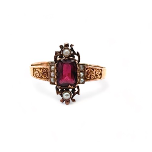 52 - A garnet and seed pearl ring with scroll shoulders, size O. Unmarked yellow metal, tests as 9ct gold... 